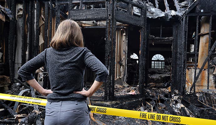 A person is inspecting a fire damaged house