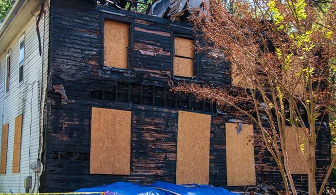 A fire damaged house with boarded-up windows A fire damaged house with boarded-up windows