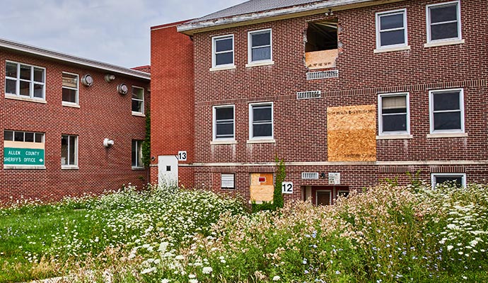 Abandoned school building with boarded-up windows and a neglected exterior