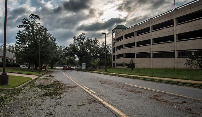 Disaster-affected healthcare facility parking with storm debris Healthcare facility parking lot and surrounding areas affected by a storm, showing debris on the road