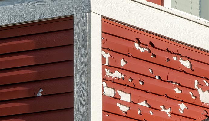 Hail-damaged hospital siding after storm Close-up of hail-damaged hospital siding with peeling paint