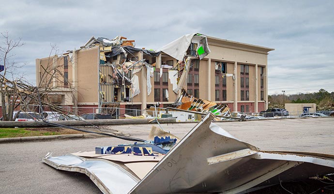 Wind-damaged building with debris on the road Building exterior severely damaged by strong winds with debris scattered on the ground
