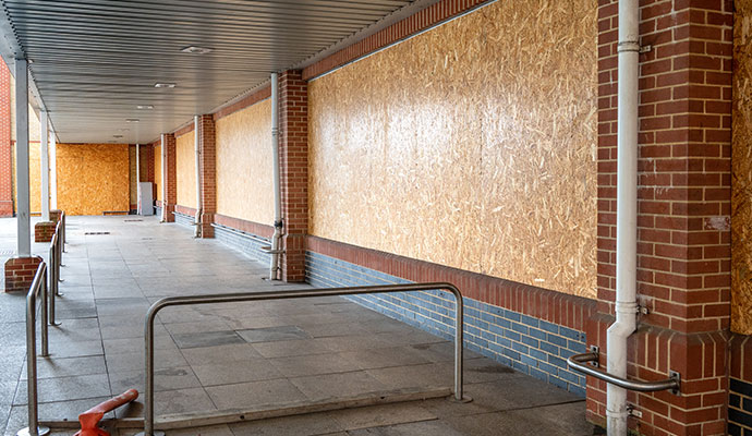 Covered walkway with boarded-up windows on a brick building
