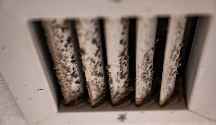 Close-up of a dirty air vent with heavy dust buildup on the slats