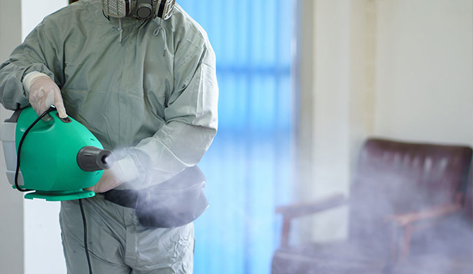 Worker in protective gear fogging a room for smoke odor removal