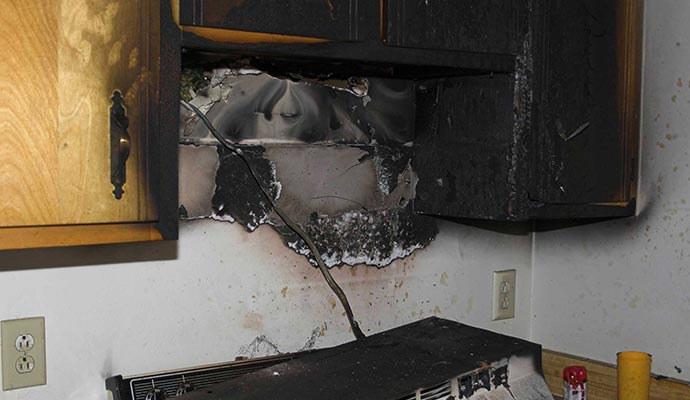 Burnt kitchen cabinet after fire damage Fire damaged kitchen cabinet with visible burn marks