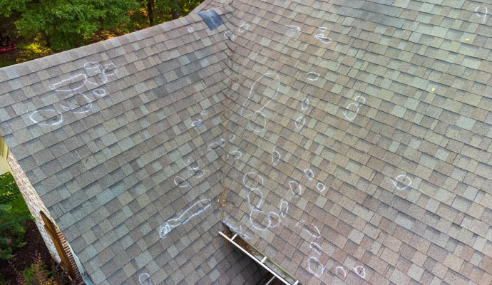 Roof shingles showing several hail-damage areas highlighted with white circles