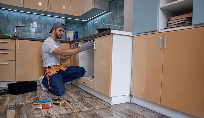 A handyman is fixing a cabinet