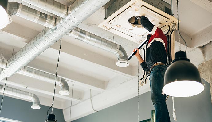 A technician is inspecting ceiling mounted HVAC unit