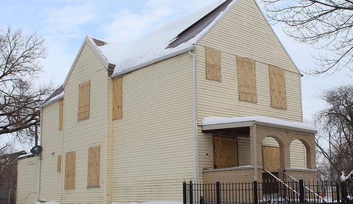 Two-story house with boarded-up windows and doors